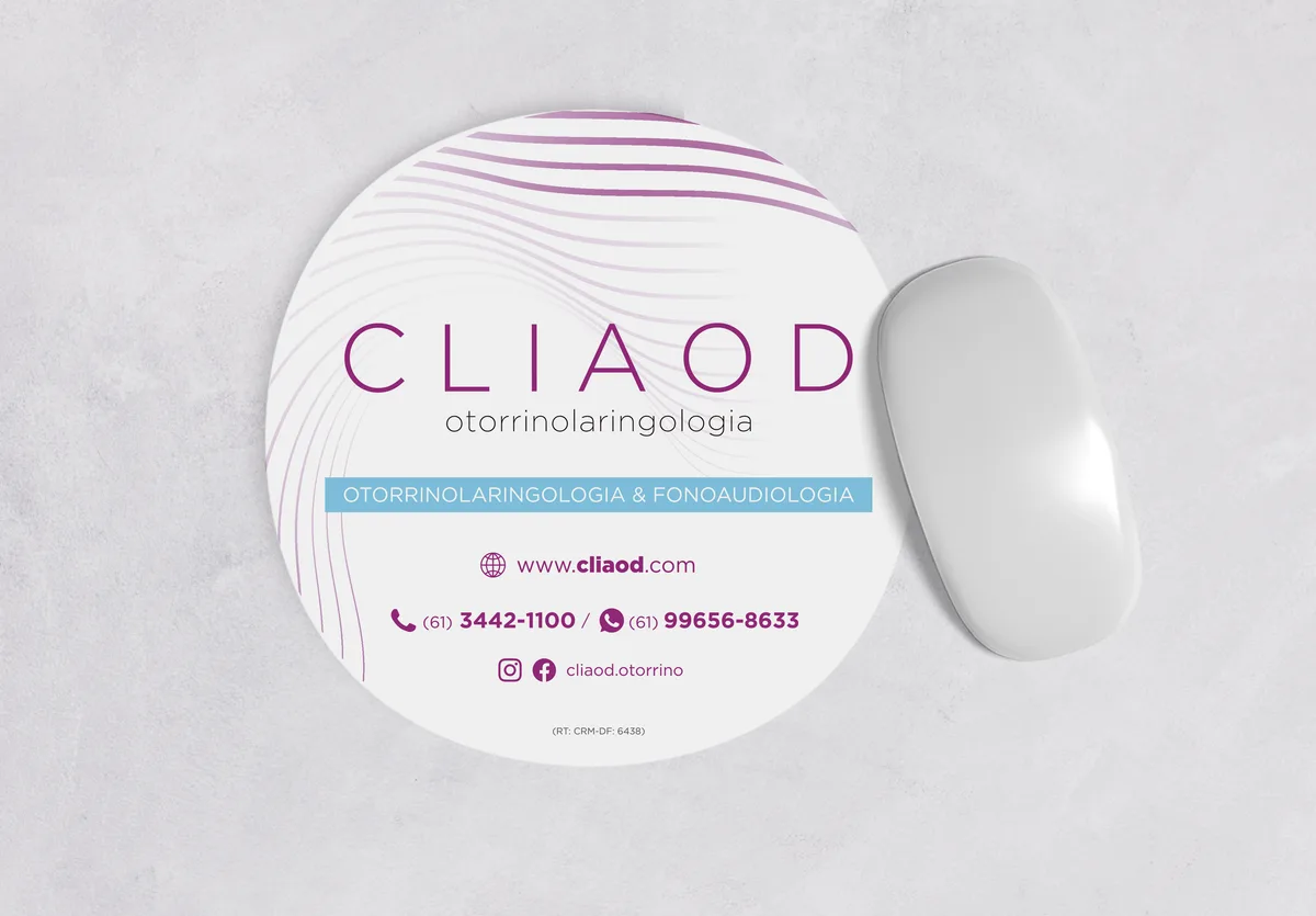 Mousepad redondo da CLIAOD sobre mesa, com site e telefones da clínica de otorrinolaringologia em Brasília